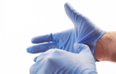 Mavi lateks eldiven takan eller grip, virüs ve koronavirüse karşı koruma sağlıyor. Sağlık ve cerrahi konsept. Cilde dokunmamak için koruyucu eldivenleri çıkarmanın doğru yolu.