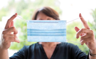 Coronavirus salgını: Bulaşıcı virüslerden korunmak için orta yaşlı bir kadın tek kullanımlık maske takıyor.