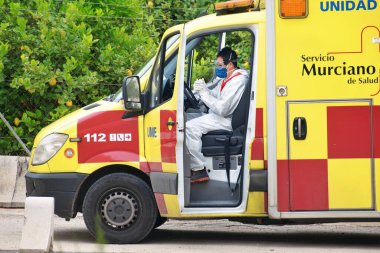 Murcia, İspanya, 18 Nisan 2020: Korunaklı doktorlar Coronavirus nedeniyle İspanyol ambulanslarında. Acil servis, virüsün yayılmasını önlemek için ev dağıtım hizmetlerinde çoklu testler yapıyor.