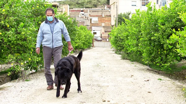 En man går med sin hund utomhus efter att Spanien infört en lockdown för att bromsa spridningen av coronavirus sjukdom i Murcia, Spanien, 19 april 2020. — Stockfoto