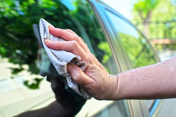 洗濯後 女性は古い布で車の窓を乾かします 最近洗浄された車の中で布で水を乾燥させます 女性の手のクローズアップビュー ストックフォト