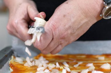 İtalyan şefin geleneksel pizza pişirmesi. Biraz soğan ekliyorum. Üstüne malzemeler ekle