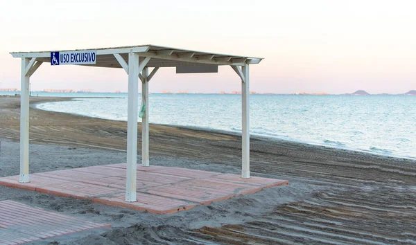 Arbor para cadeira de rodas uso exclusivo na praia de Los Narejos, na Espanha. Lugares na praia para pessoas com deficiência o sinal é azul em um fundo branco para deficientes há lugares para — Fotografia de Stock