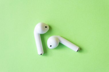 Yeşil arka planda kablosuz beyaz kulaklık. Renkli bahar konsepti