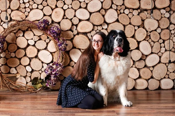 Portrait of a beautiful young woman in the room, playing with a dog