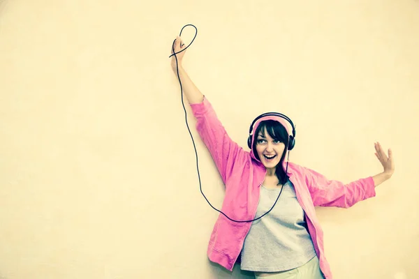 a girl in a hood listening to music on headphones and raising her hand up
