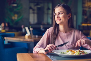 Young woman smiling and looking away while eating lunch