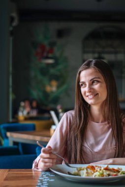 Cute young woman smiling and looking away while eating