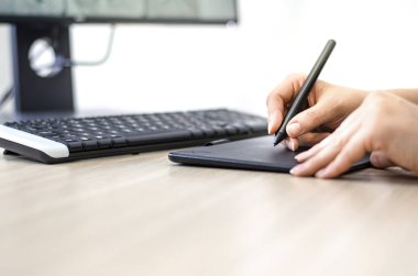 Çizim yapmak ve çizimler yapmak için grafik tablet ve kalem kullanan tasarımcıların el kapanışı 