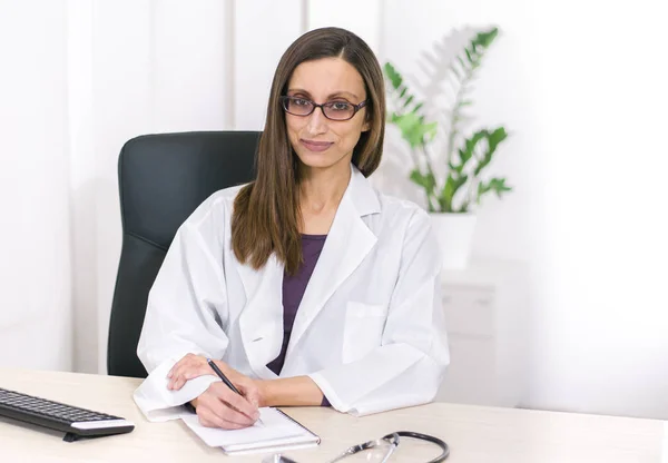 Vacker Kvinnlig Läkare Med Glasögon Leende Anteckna Och Titta Kameran — Stockfoto