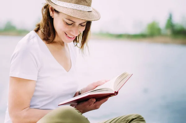 Χαριτωμένο Κορίτσι Διαβάζει Ένα Βιβλίο Δίπλα Στη Λίμνη Μια Καλοκαιρινή — Φωτογραφία Αρχείου