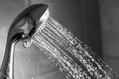 Banyoda akan suyla duş başlığı yakın plan. Siyah beyaz fotoğraf. 