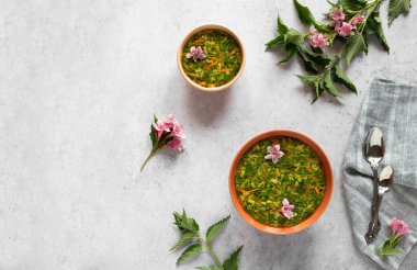 Isırgan otlu bahar çorbası ve çiçek desenli iki kâse. Metin için kopyalama alanı olan Rustik desenli arkaplan. 