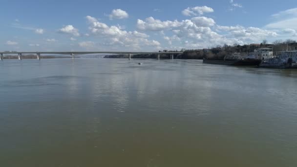 高速ボートを運転する男 川の真ん中 カメラは それに向かって飛ぶ 背景の橋 水を反映します — ストック動画