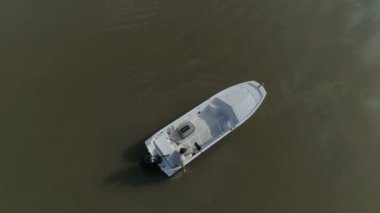 Bir adam clonk balıkçılık bir tekneden kamera yukarıda uçar. Bir nehir ortasına. Köprü içinde belgili tanımlık geçmiş. Bulutlar suda yansıtacak.