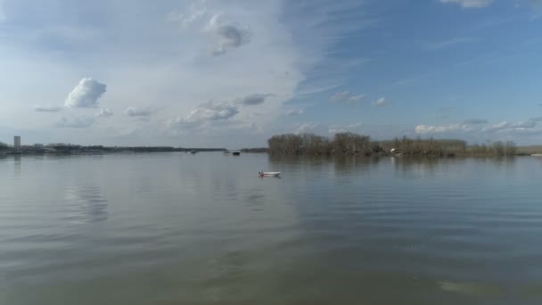 Caméra monte à la rivière. Un homme dans un bateau au loin. Quelques nuages, ciel bleu. Images de drones .