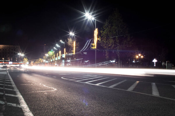 Junction square. Cars passing. Some pedestrians. Christmas/New Year decorations. Modern lighting.