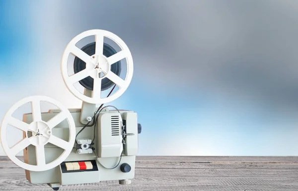 Vintage film projector on a table on a background of a blurry sky