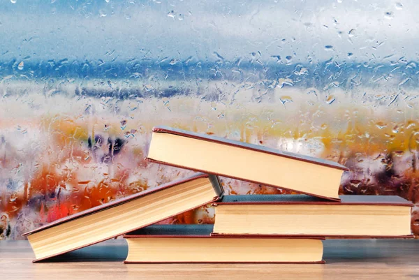Uma pilha de livros no fundo de uma janela chuvosa — Fotografia de Stock