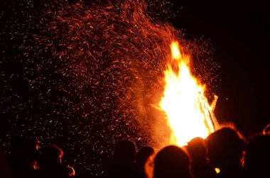 Bir şenlik ateşi ile gece gökyüzü arka planı insan siluetleri ile kıvılcım