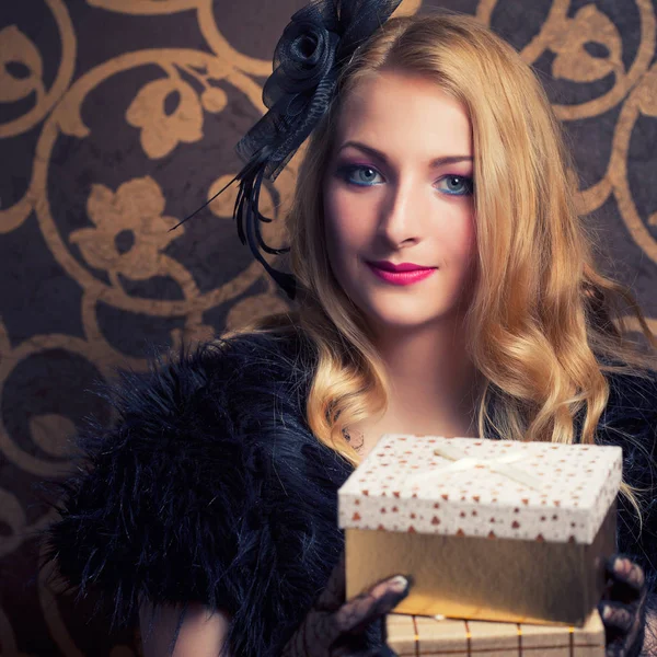 Woman holding a golden gift boxes — Stock Photo, Image