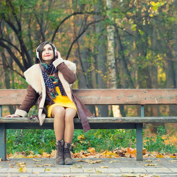 Jovem mulher desfrutando de uma música na temporada de outono — Fotografia de Stock