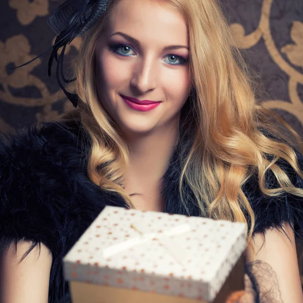 Vrouw met een gouden geschenkdozen — Stockfoto