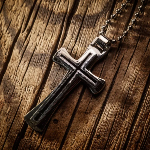 Ahşap arka plan üzerinde gümüş haç 