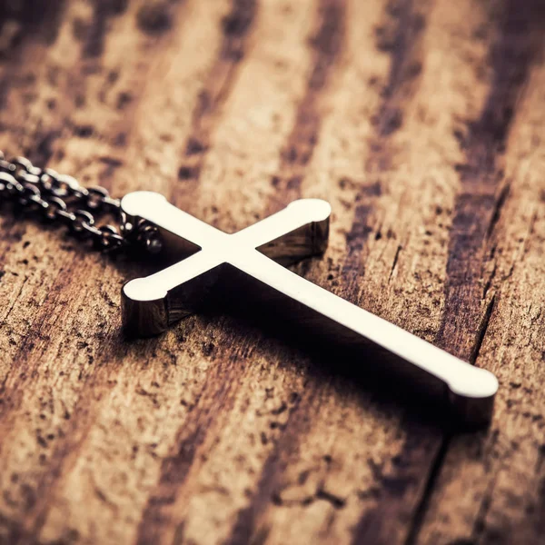 Ασημένιο σταυρό σε ένα ξύλο παρασκήνιο — Φωτογραφία Αρχείου
