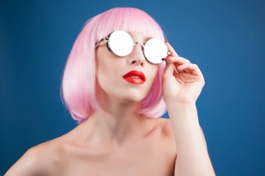 renkli peruğu ve mavi arka plan karşı gümüş güneş gözlüğü giyen güzel kadın