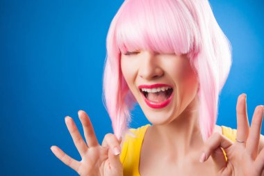 mavi arka plan karşı pembe peruk giyen güzel kadın