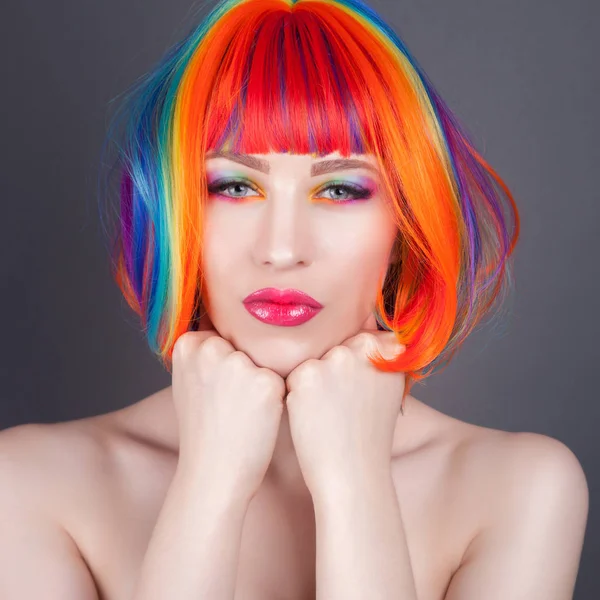 Hermosa mujer vistiendo peluca colorida y mostrando uñas coloridas — Foto de Stock