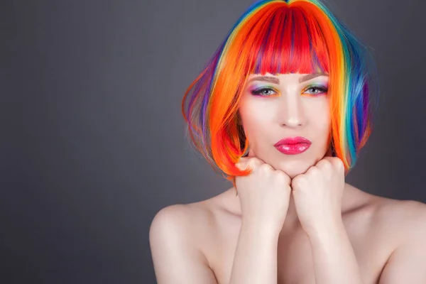 Hermosa mujer vistiendo peluca colorida y mostrando uñas coloridas —  Fotos de Stock