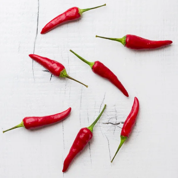 Raw red chili peppers on white rustic wooden table — Stock Photo, Image