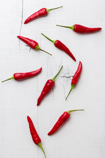 Raw red chili peppers on white rustic wooden table — Stock Photo, Image