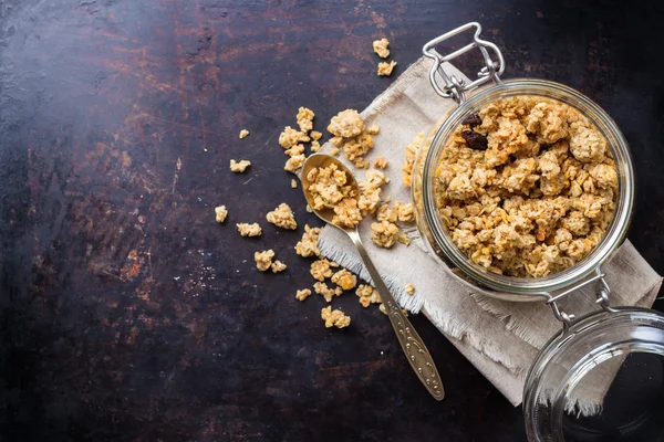 Granola de muesli caseiro em um frasco na mesa preta enferrujada — Fotografia de Stock