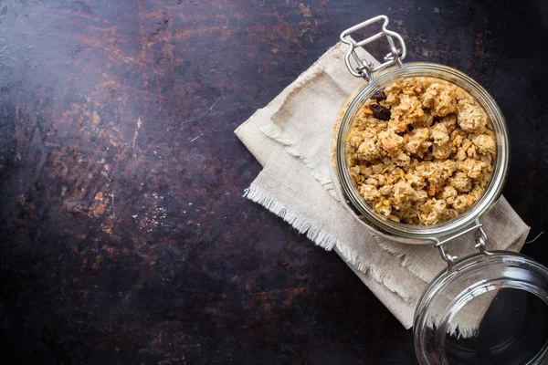 Granola de muesli caseiro em um frasco na mesa preta enferrujada — Fotografia de Stock