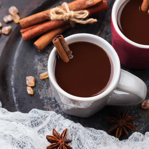 Cokelat panas di cangkir dengan rempah-rempah di atas meja gelap — Stok Foto