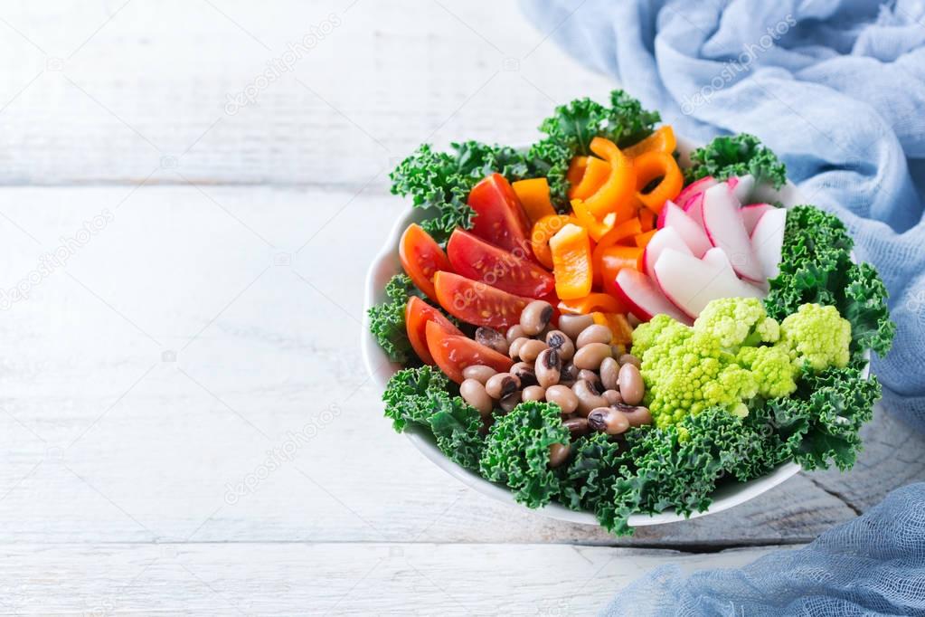 Healthy vegan buddha bowl with kale leaves and raw vegetables