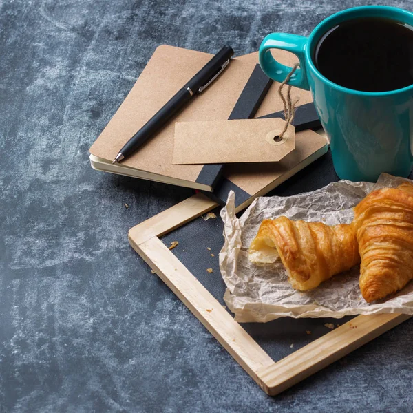 Papeterie d'affaires croissants tasse de café noir sur tableau noir grunge — Photo