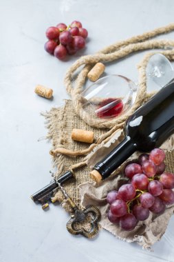Şişe, tirbuşon, bardak kırmızı şarap, üzüm bir tablo