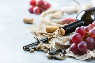 Şişe, tirbuşon, bardak kırmızı şarap, üzüm bir tablo
