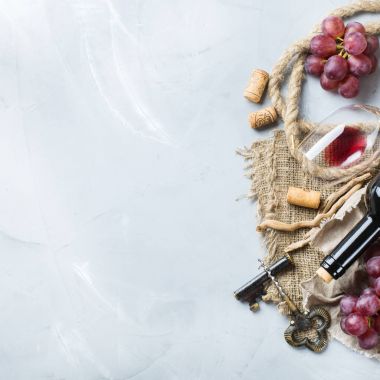 Şişe, tirbuşon, bardak kırmızı şarap, üzüm bir tablo