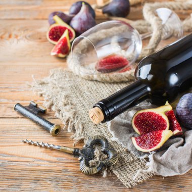 Şişe, tirbuşon, bardak kırmızı şarap, bir tabloda incir