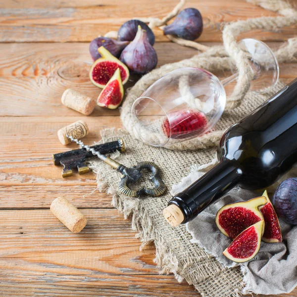 Bottle, corkscrew, glass of red wine, figs on a table — Stock Photo, Image