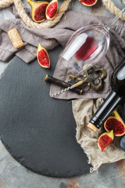 Şişe, tirbuşon, bardak kırmızı şarap, bir tabloda incir