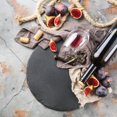 Şişe, tirbuşon, bardak kırmızı şarap, bir tabloda incir