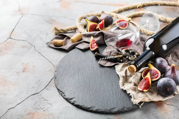 Şişe, tirbuşon, bardak kırmızı şarap, bir tabloda incir