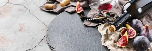 Fles, kurkentrekker, glas rode wijn, vijgen op een tafel — Stockfoto