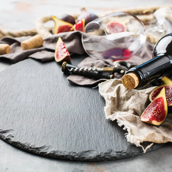 Şişe, tirbuşon, bardak kırmızı şarap, bir tabloda incir